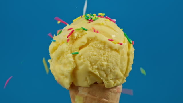Colorful sprinkles falling on banana ice cream. Ice cream at blue background.