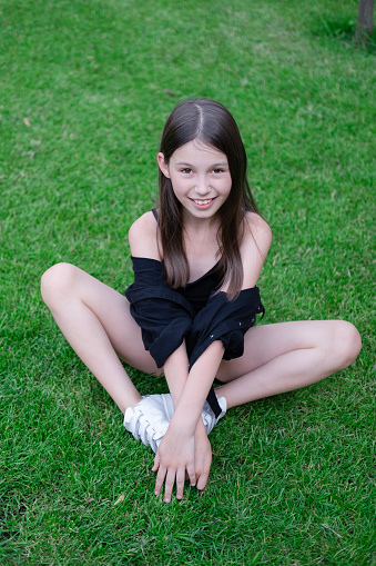 portrait of adorable teen brunette girl in black clothes outside. charming ukrainian child enjoying summer holidays vacation on green grass. pretty kids concept.