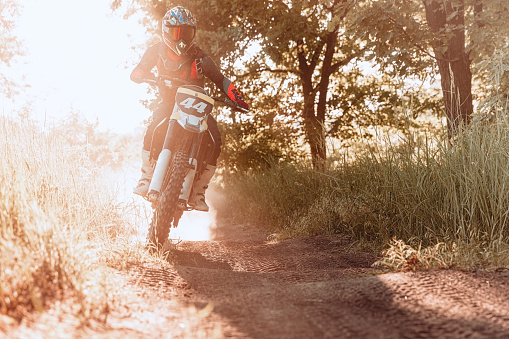 Driving empty road on motorcycle tour journey. Live shot of male sportsman training on motorbike at hot summer day, outdoors. Motocross sport, competition, male hobby, energy and ad