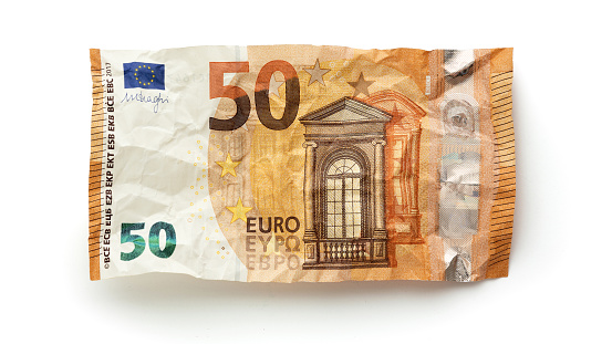 Stack of coins on euro banknotes as wide panoramic format, website header concept for business, finance or inflation, copy space, selected focus, narrow depth of field