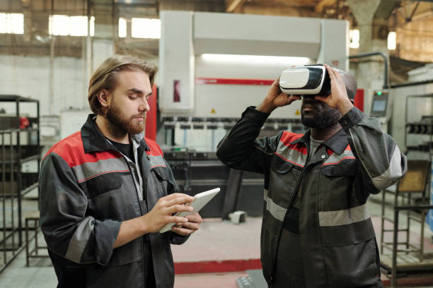 istock Young engineer scrolling in tablet while standing by colleague in vr headset 1406725309