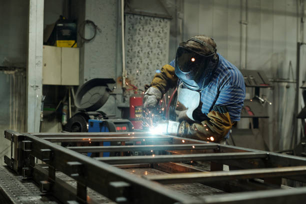 istock Young male welder in protective mask and gloves welding metallic structure 1406725334