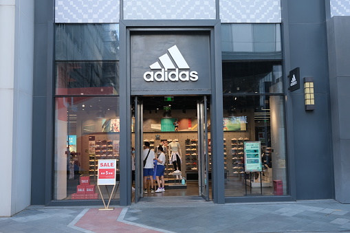 Shanghai,China-July 2nd 2022: facade of Adidas retail store and customers shopping inside.