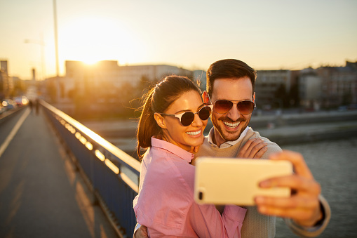 Smiling couple on bridge taking Selfie