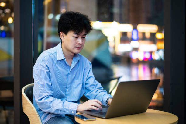 istock Asian young handsome man using laptop to work in coffee shop at night 1406728818
