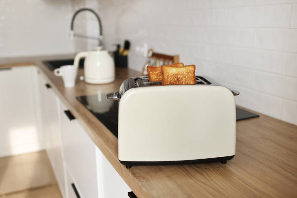 istock Modern white toaster and roasted bread slices toasts inside on wooden table in kitchen 1406728888