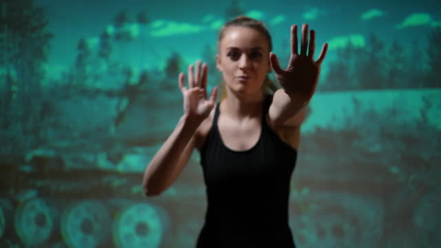 Hands of blurred woman imitating touching glass posing at background of bombed house ruins. Young slim Ukrainian dancer performing looking at camera posing at destroyed debris picture.