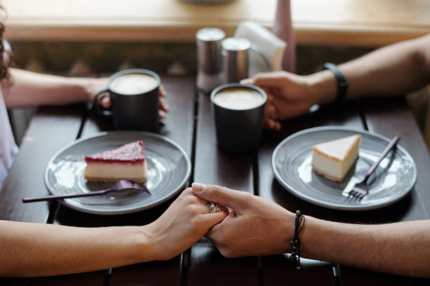 istock Young affectionate dates with cups of coffee holding by hands by table 1406731292