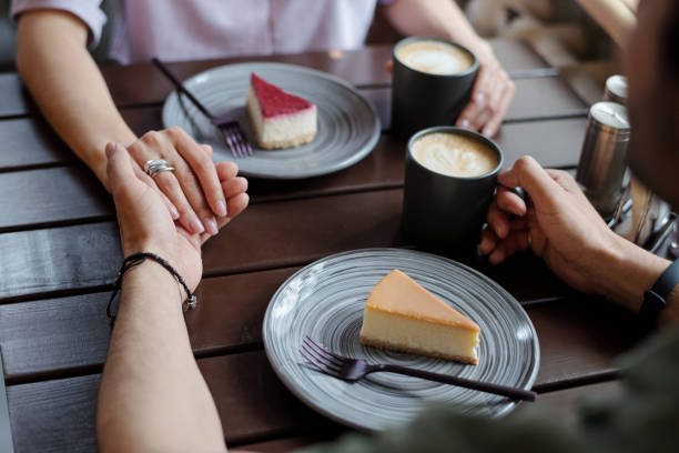 istock Hands of young affectionate dates with cups of cappuccino sitting by table 1406731323