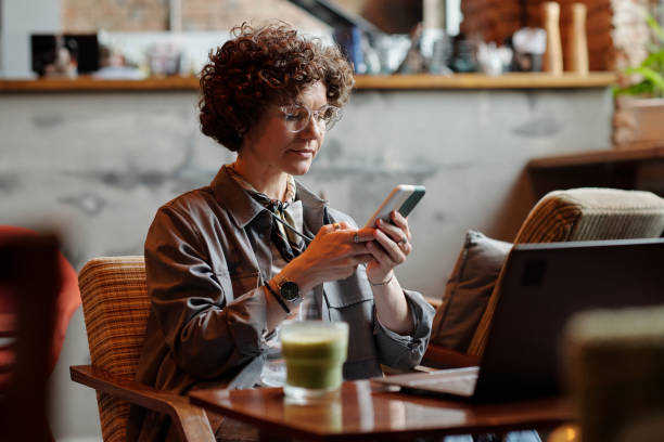 istock Serious businesswoman texting or scrolling in smartphone while sitting in cafe 1406731695