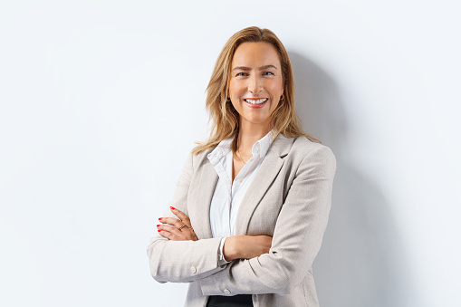 Shot of a beautiful smiling businesswoman standing in front of her team in the office. Portrait of successful businesswoman standing with her colleagues working in background.