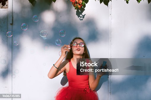 istock Happy girl having fun blowing bubbles 1406735185