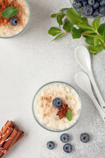 porridge di riso o budino con cannella e mirtilli in una ciotola sul tavolo. colazione sana. vista dall'alto - rice pudding foto e immagini stock
