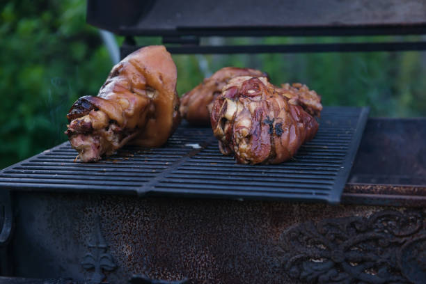 いくつかの伝統的なバイエルンドイツのローストポークナックルは、回転煮沸ラックグリルの唾を吐き出し、クローズアップ、ローアングルの側面図でゆっくりと調理されました。バーベキ� - barbecue grill broiling barbecue vegetable ストックフォトと画像