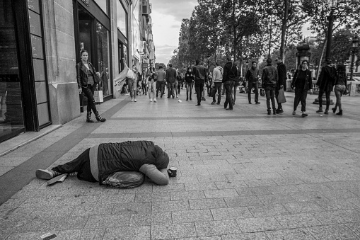 05-14-2016  Paris Beggar on Champs Elysees street in Paris. People walking in May.
