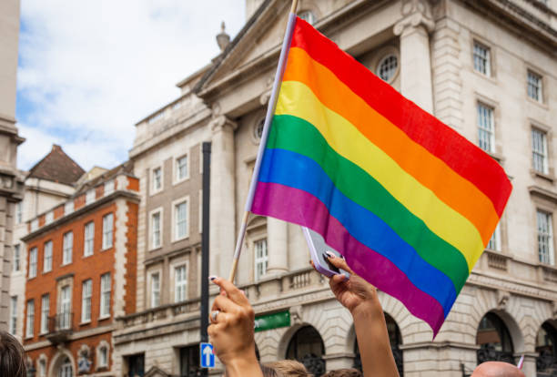 personas ondeando la bandera del arco iris en el desfile del orgullo gay en la calle de la ciudad - carroza de festival fotografías e imágenes de stock