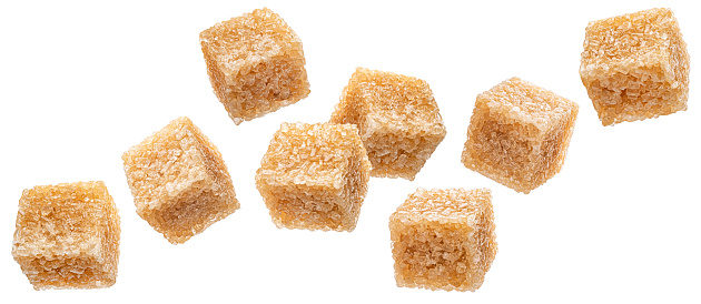 Falling cubes of brown cane sugar isolated on white background, full depth of field