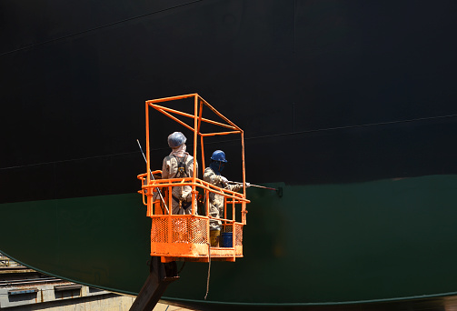 Shipyard Workers painting a ship