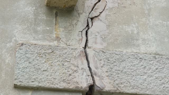 Crack in the foundation of a building from an earthquake close-up. Broken fractured wall of the house