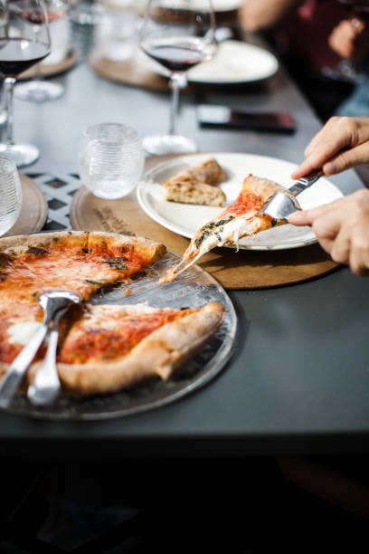 istock Man cuts a piece of pizza from the festive table 1406745610