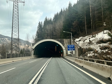 Alpine road leading to a mountain tunnel. Road signs.