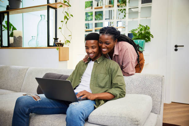 istock Smiling young couple watching something together on a laptop at home 1406753336
