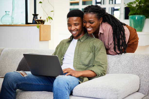 istock Young couple watching something on a laptop while relaxing at home 1406753443