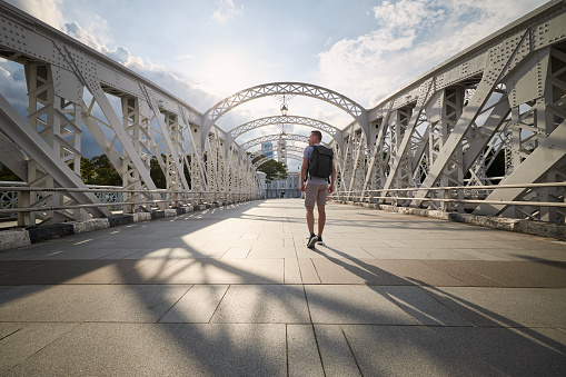 Rear view of man while walking on steel bridge
