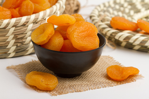 Apricot served in bowl isolated on napkin side view of dry fruits on grey background