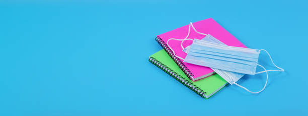 istock Two colourful notebooks and face masks isolated on blue background. 1406755583