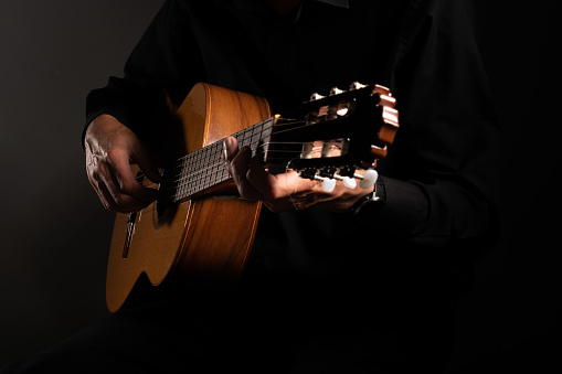 Spanish classical guitar and guitarist's hands up close on a black background with copy space
