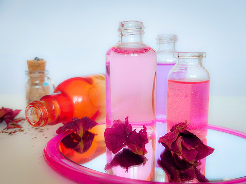 Small glass bottles with different liquids. Dried rose petals