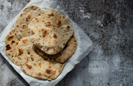 Homemade Chapati Roti Flatbread on grey background. Freshly baked indian street food. Copy space for text.