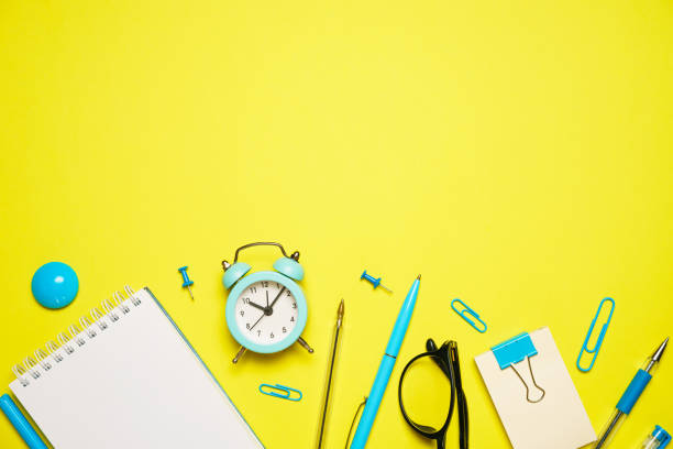 istock Notebook for writing pen and alarm clock with glasses on yellow background top 1406763539
