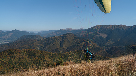 A paraglider landing on the ground against the blue sky.