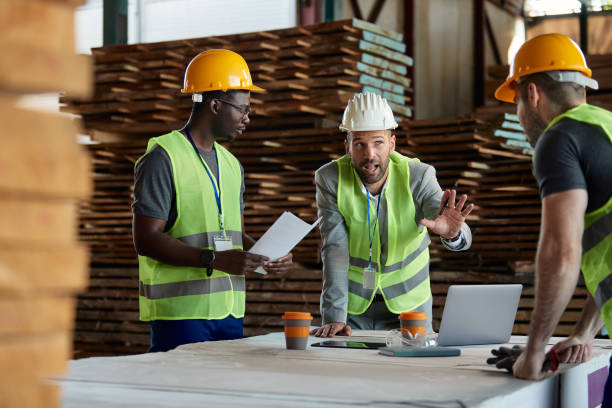 istock Warehouse inspector communicating with workers during a meeting at lumber compartment. 1406765369