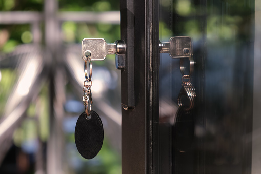 Key with a large oval keychain is inserted into the keyhole. The concept of buying residential real estate, space for text.
