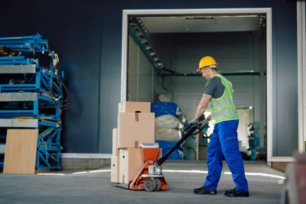 istock Male worker pushing packages on pallet jack while working warehouse. 1406766509