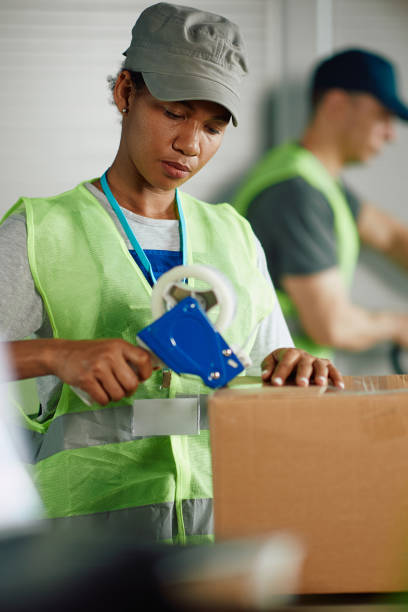 istock Black woman taping carboard boxes while working at distribution warehouse. 1406766833