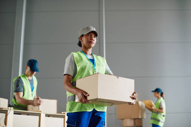 istock Below view of black woman carrying package while working at distribution warehouse. 1406767399