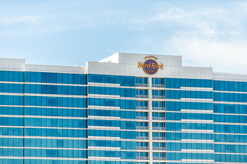 Tampa, USA - October 4, 2021: Seminole Hard Rock Cafe hotel and casino resort sign for famous restaurant in Florida exterior facade of modern glass building and blue sky