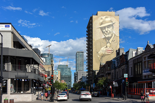 Montreal, Canada - July 3, 2022: The trendy Crescent Street with mural of the legendary singer/songwriter Leonard Cohen on side of building.