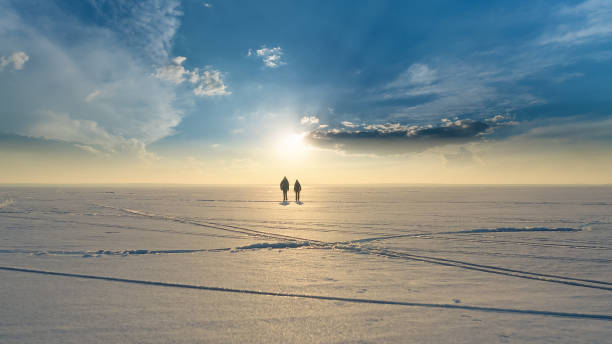 les deux voyageurs avec des sacs à dos traversant le champ de neige - ice winter white women photos et images de collection