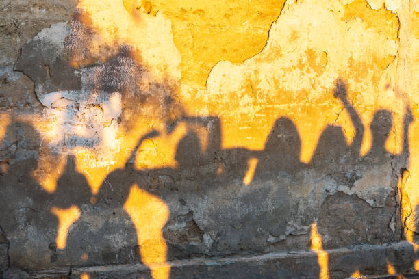 istock Shadows of dancing people on an old stone wall at sunset time. 1406770988