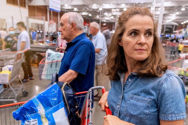 Mature woman holding her shopping cart waiting in line to pay at a megastore stock photo