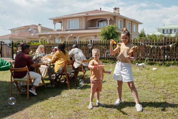 istock Two kids playing with soap bubbles while standing on green grass of backyard 1406775810