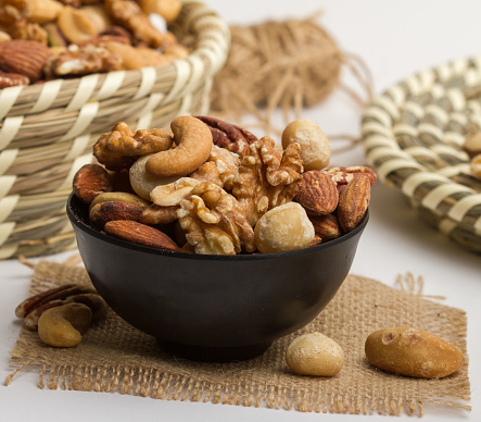 Classic mixed nuts served in a bowl isolated on napkin side view of nuts on grey background