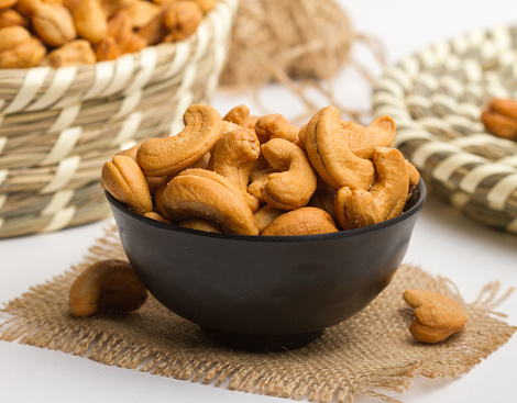 salted cashewnut served in a bowl isolated on napkin side view of nuts on grey background