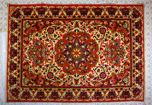 The Old carpet on the wall with an abstract pattern. Rare vintage embroidered carpet. Red vintage carpet.