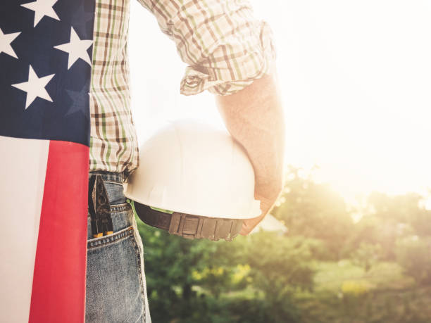 istock Attractive man in work clothes, holding American Flag 1406777874